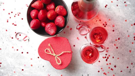 Bottle-of-rose-champagne--glasses-with-fresh-strawberries-and-heart-shaped-gift