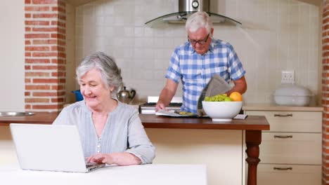 Senior-on-laptop-and-reading-newspaper