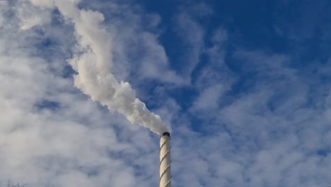 view of white smoke from chimney on blue sky background. ecology and greenhouse effect concept.