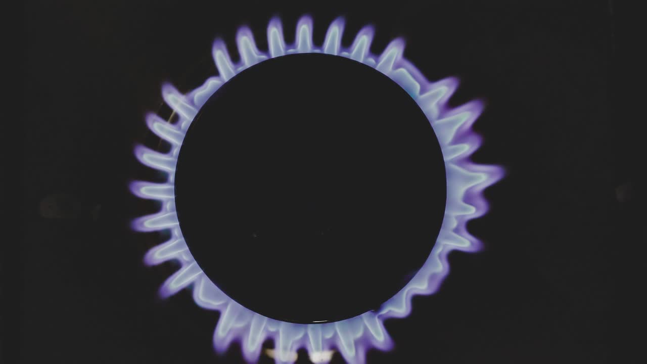 가스 스토브가 켜진 버너에 의해 켜지고 있습니다.