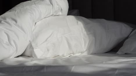 unmade bed with white pillows and sheets