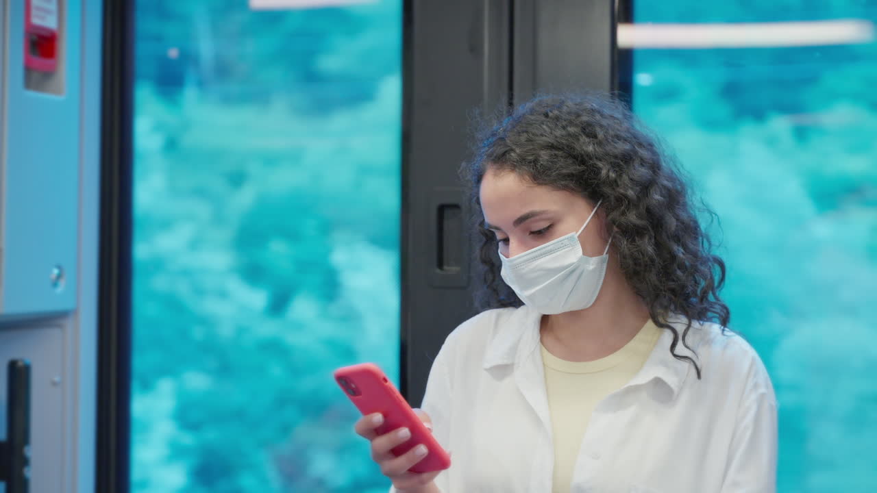 mujer en el tren usando el teléfono mientras lleva una máscara