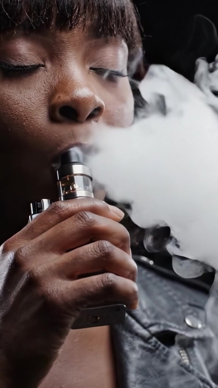 Captivating Moments: A Woman Inhaling Vapor, Embraced By Smoke, Showcasing the Artistry and Culture of Vaping in a Chaotic World
