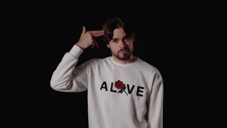 trendy young man pointing finger gun at head, wide, black background