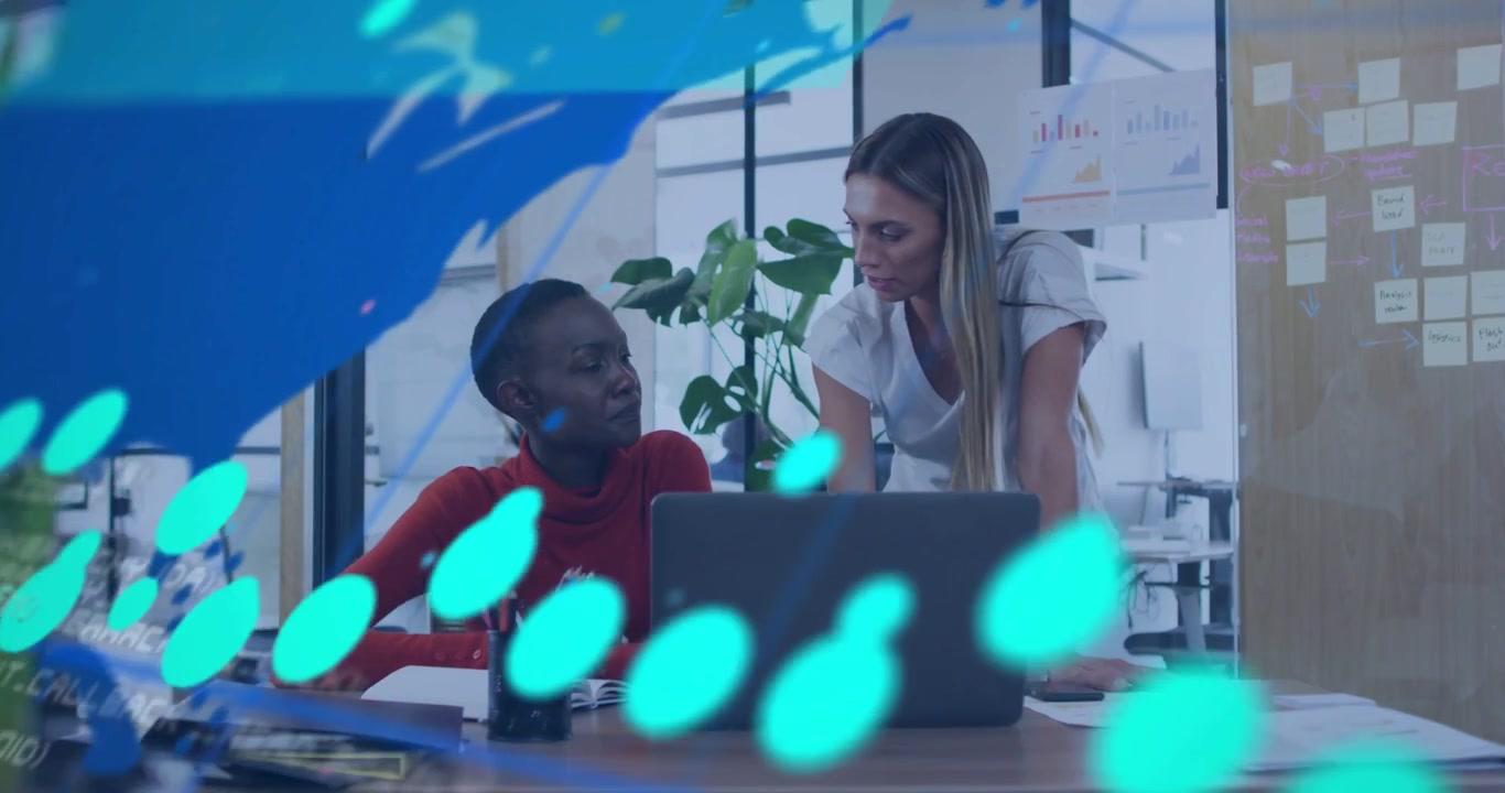 Standing peer pointing to laptop causing moving data graphs while seated peer noting for analytics