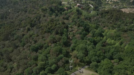 Penha-cable-car-ride-above-lush-forest,-Guimarães,-Portugal---Aerial