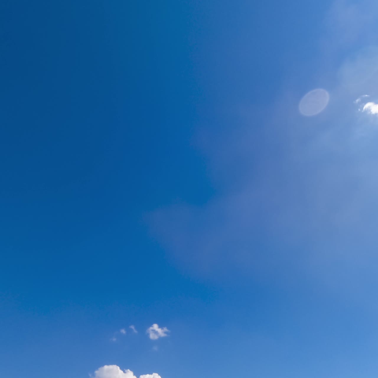 Tiny light soft clouds appearing in the bright blue sky. Sunrays going through the clouds. Timelapse