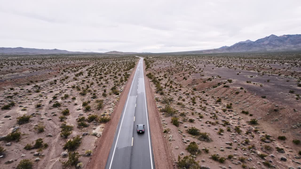 Aerial Drone Shot of a Car Driving on a Long Isolated Road in the Desert