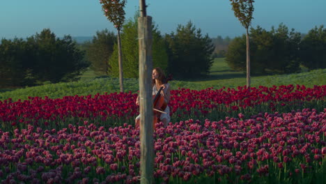 Unerkennbare-Junge-Frau-Spielt-Im-Frühling-Violoncello-Auf-Einem-Blühenden-Feld.