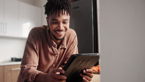 happy man using tablet in kitchen