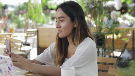 Joven-Mujer-Sentada-Mirando-Su-Teléfono-Móvil