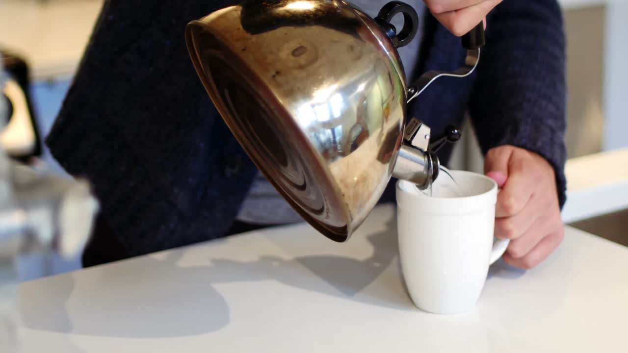 컵 에 ketel 에서 뜨거운 물 을  ⁇ 는 사람 의 중간 부분