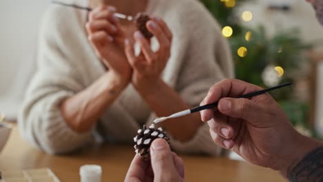 multi ethnicity couple decorating cone with white paint during christmas time at home.