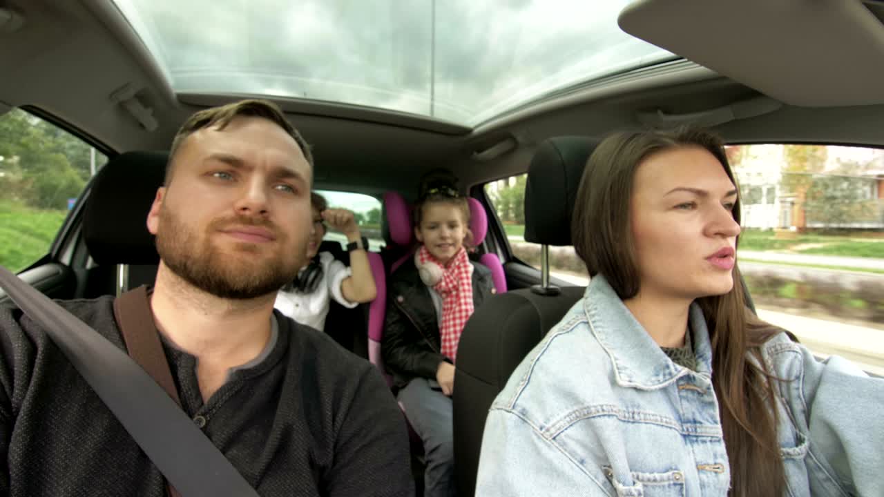 남자와 여자와 아이들이 차를 운전하고, 두 부모와 아이들이 트레 트랜스포트에서 여행하고 춤을 춘다. 행복한 가족, 도로 여행