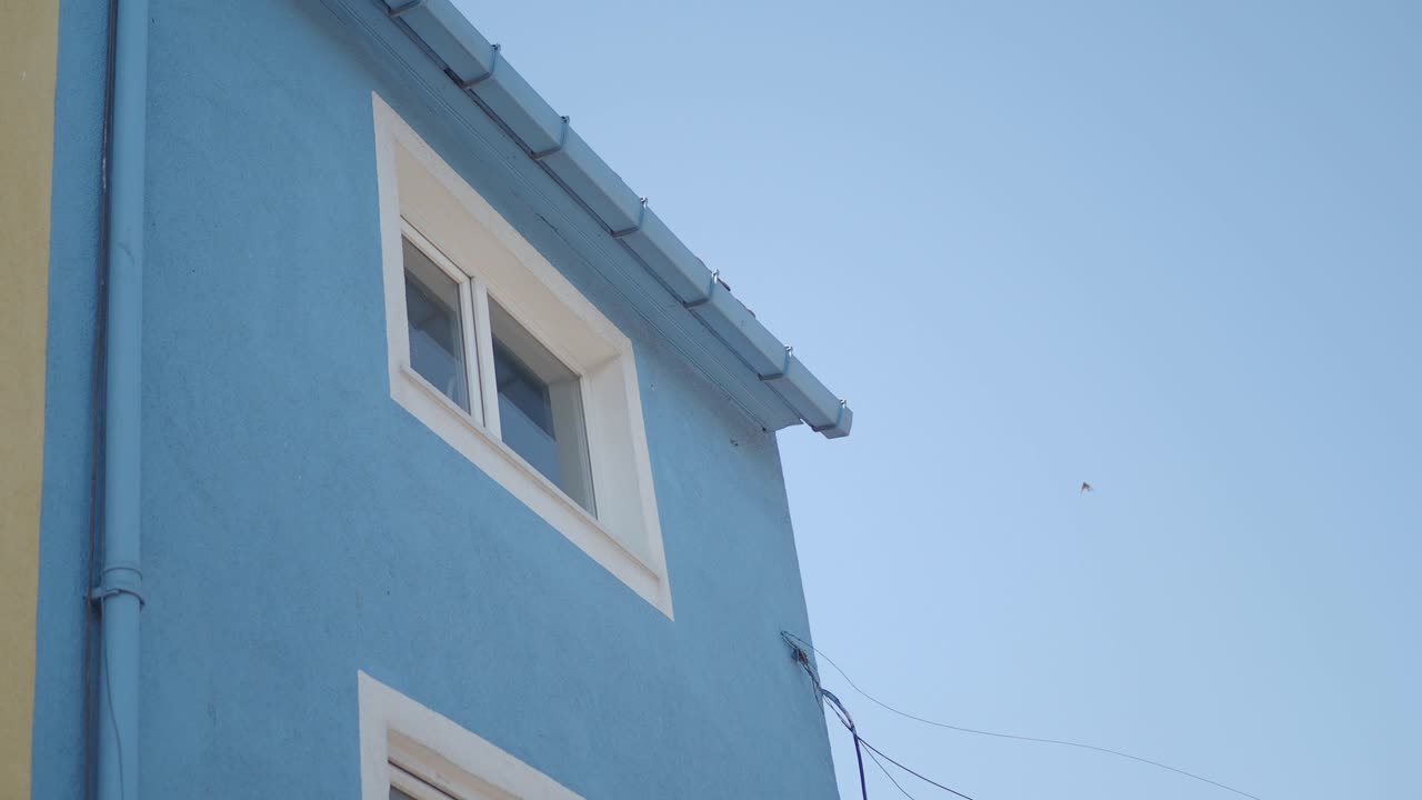 Exterior of a light blue building with a white window