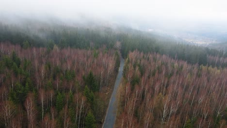 aerial drone flying through white rainy fog to show mountain road