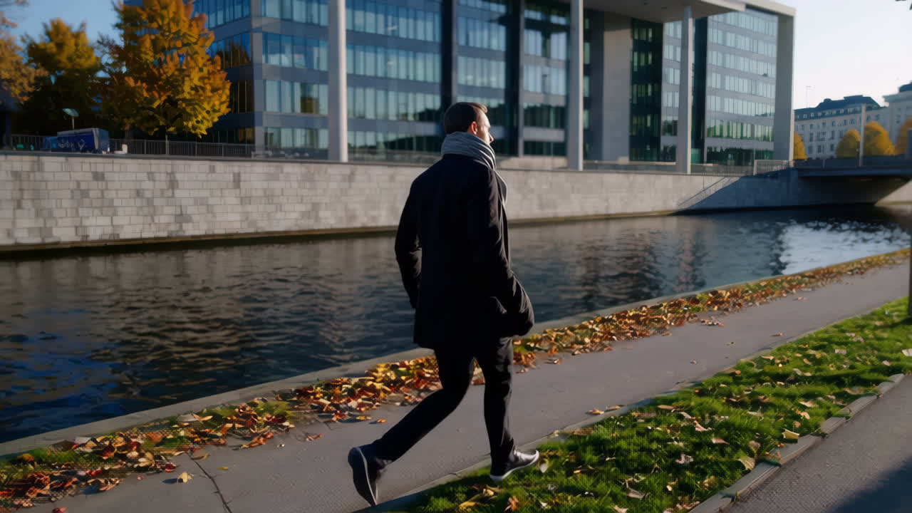 Man walking along a canal in the city in autumn
