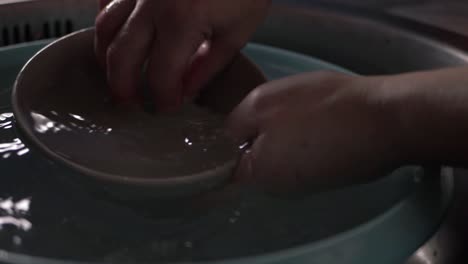 Hands-washing-crockery-in-kitchen-sink-close-up-shot