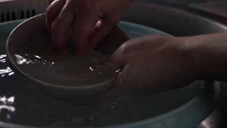 hands washing crockery in kitchen sink close up shot