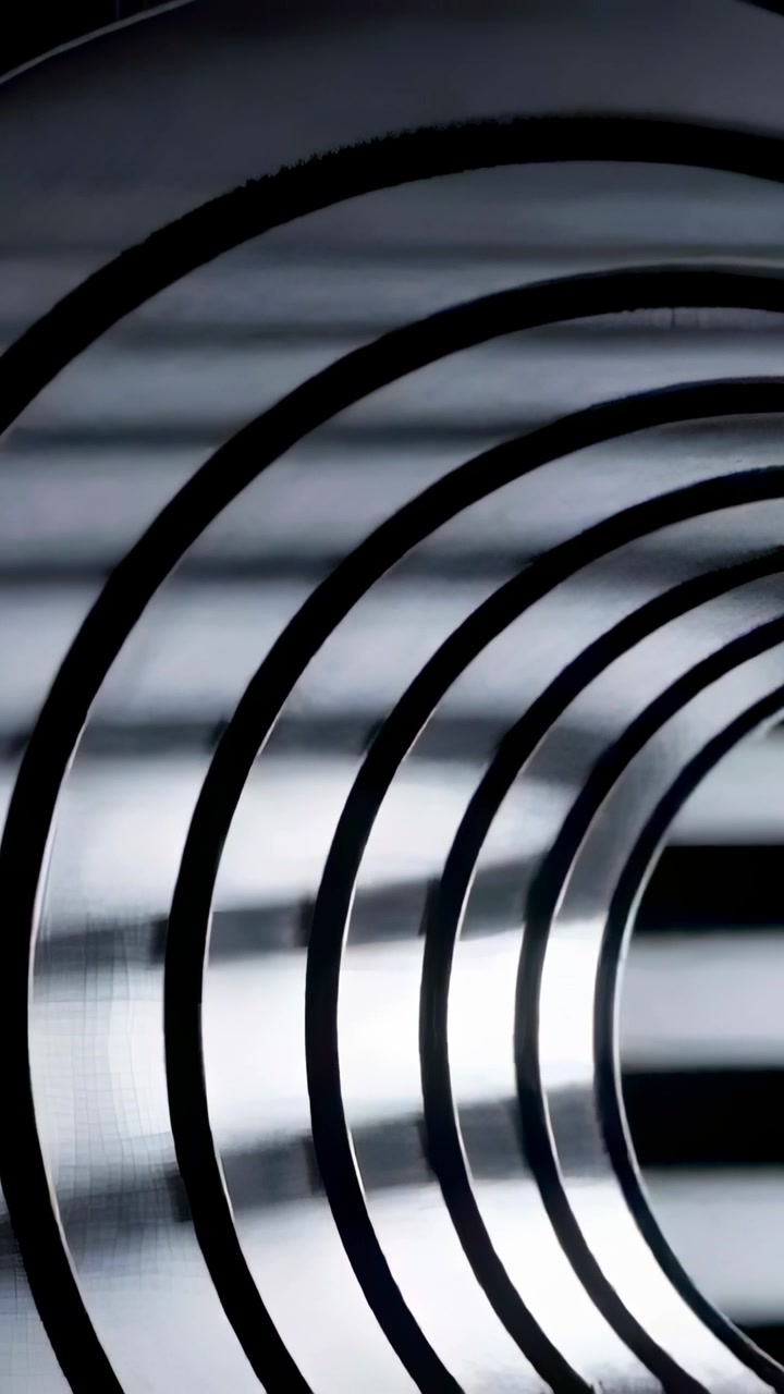 Video verticale: Telecamera in movimento che si spinge verso una bobina in studio con luce a fasce, rivelando un tunnel.