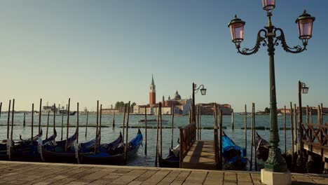 Gondolas,-typical-boats-from-Venice,-moving-on-the-water-in-the-lagoon-near-the-main-square