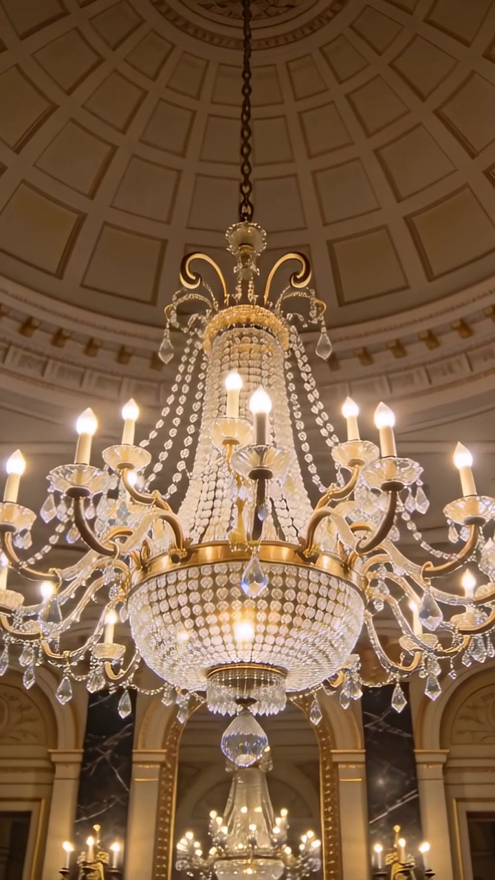 Video verticale: Telecamera che si inclina rivelando un lampadario di cristallo nell'atrio, mostrando catena, perline e archi.