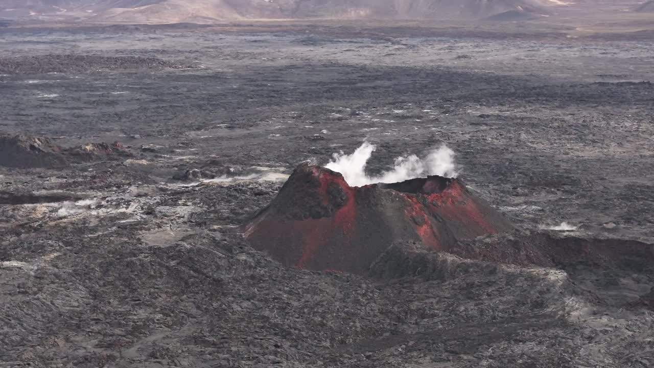 Aerial view of a smoking volcano surrounded by a vast lava field in Iceland.