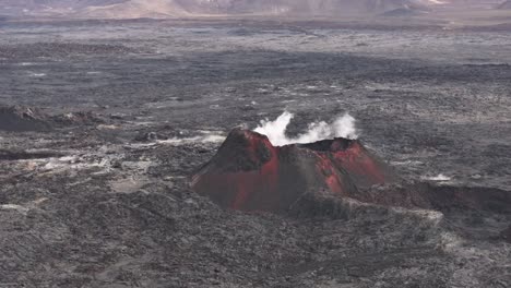aerial view of a smoking volcano surrounded by a vast lava field in iceland.