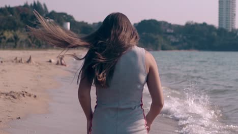 brunette-in-short-dress-runs-and-turns-on-beach-slow-motion