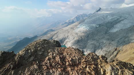a dramatic aerial shot pulls back from two stunning turquoise alpine lakes and a vast glacier to reveal a rocky mountain ridge at paso del zorro in the remote huayhuash range of peru