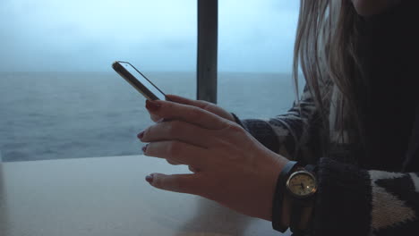 person's hands using a smartphone with an ocean view