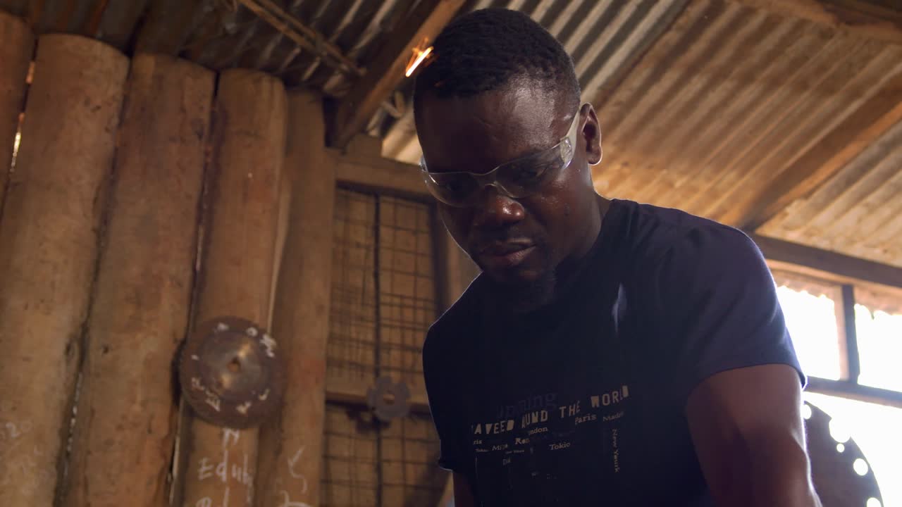 Homem africano solda metal em fábrica modesta em Gana, close-up em câmera lenta