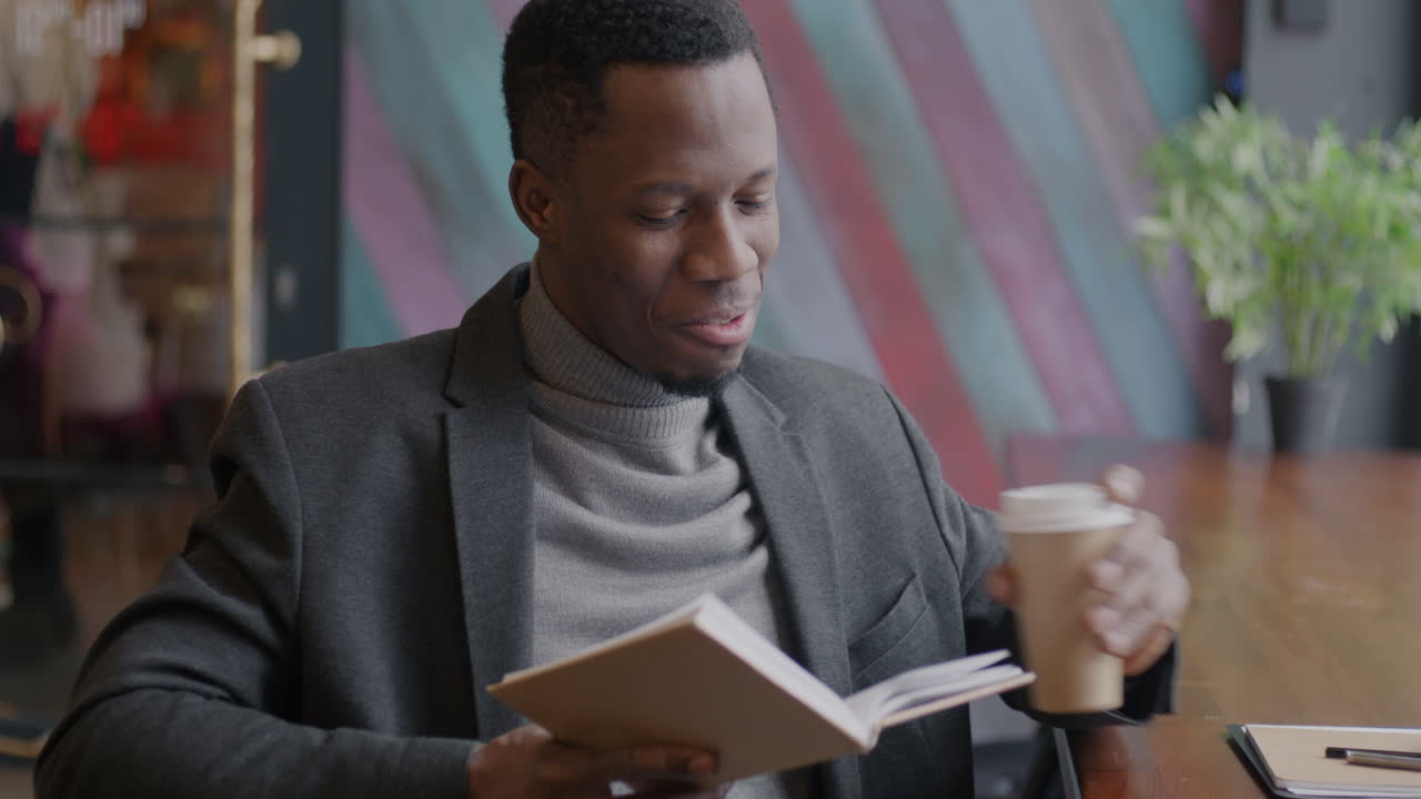 Man Reading and Drinking Coffee in a Cafe