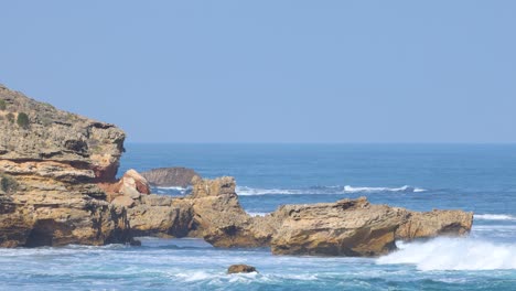 dynamic ocean waves crash against rugged cliffs under clear skies at mornington peninsula, captured in natural daylight