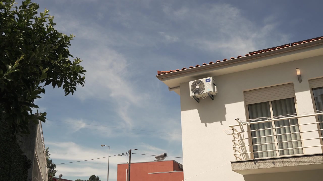 Edificio residenziale con balcone e unità di condizionamento sotto un cielo azzurro limpido