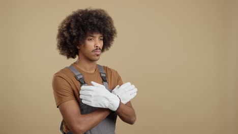 man with afro hair in overalls and gloves looking to the side