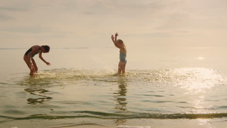 Glückliche-Kindheit---Zwei-Mädchen,-Die-Lachend-Im-Wasser-Spielen