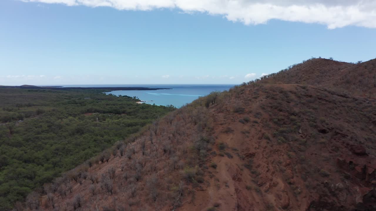 Low aerial shot flying over the Pu'u Olai cinder cone crater to reveal Makena State Park and Beach off the southern coast of Maui in Hawai'i
