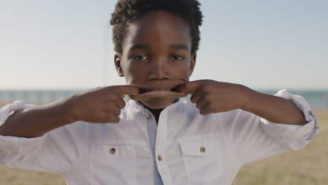 retrato en primer plano de un lindo niño afroamericano haciendo caras en la cámara feliz juguetón disfrutando de un día soleado en el parque costero