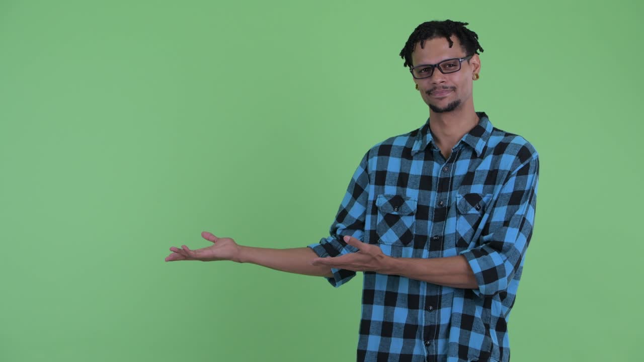 joven feliz y guapo hombre hipster africano mostrando algo