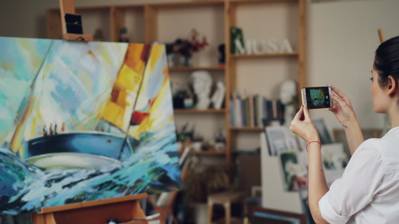 Woman taking a picture of a painting in an art studio