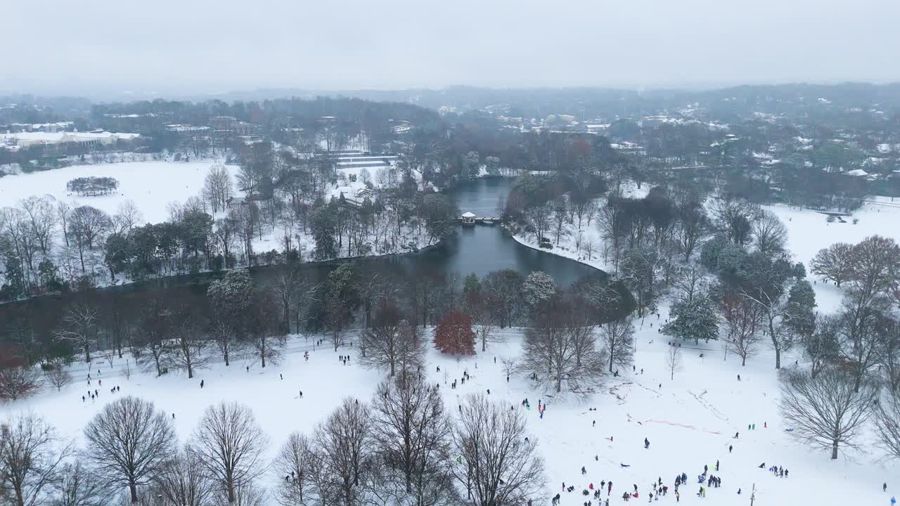 Static aerial shot of snow covered Piedmont Park and Lake Clara Meer with people sledding in Atlanta Georgia.