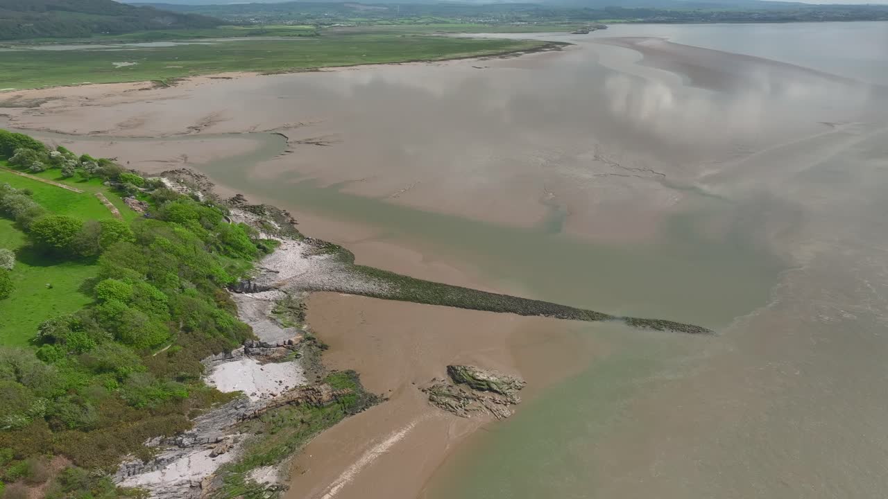 vista de alta altitud de la estructura de piedra hecha por el hombre de la pared de walduck y la marea que retrocede con reflejos de nubes en el agua en un brillante día de primavera en el punto de jenny brown, silverdale, lancashire, inglaterra, reino unido