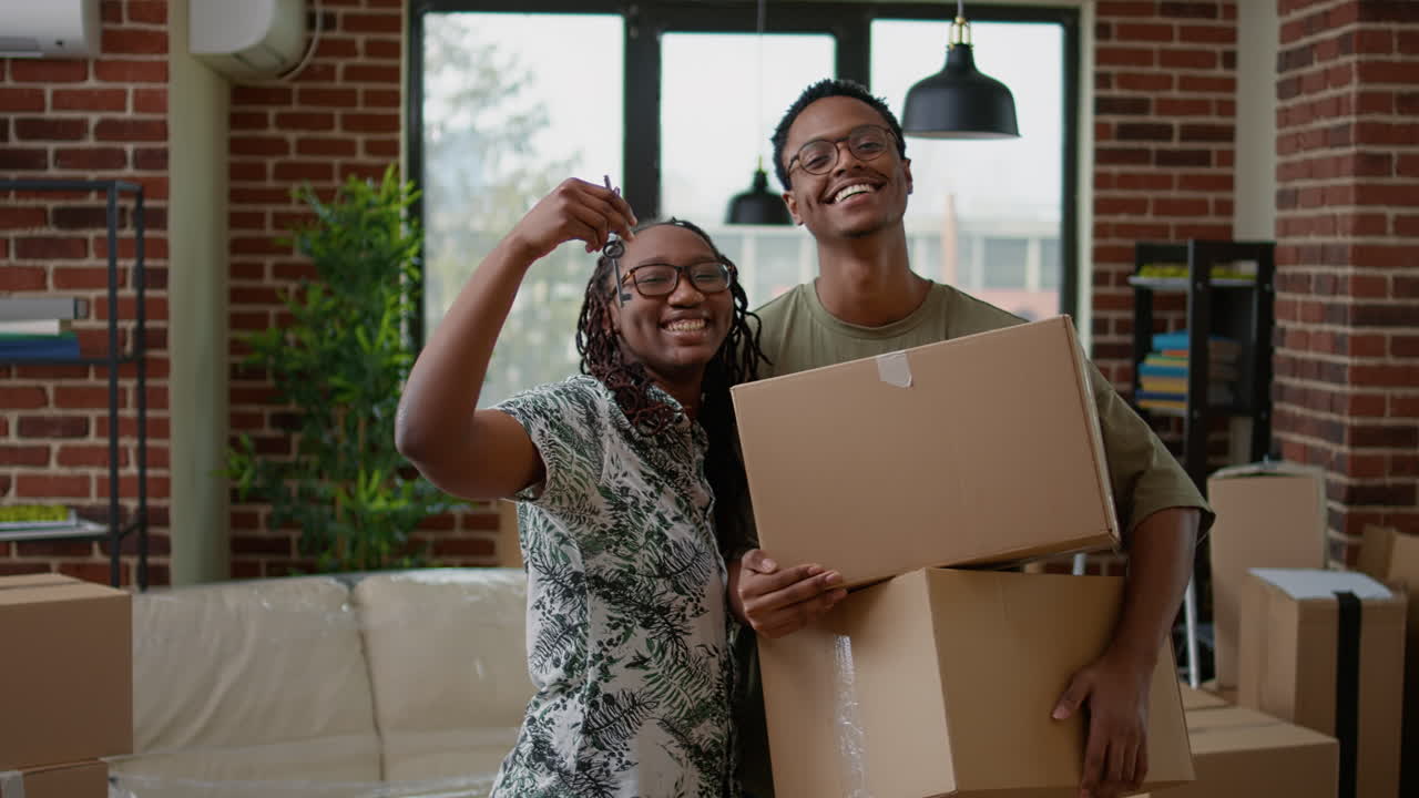 Portrait of married couple holding house keys and cardboard boxes