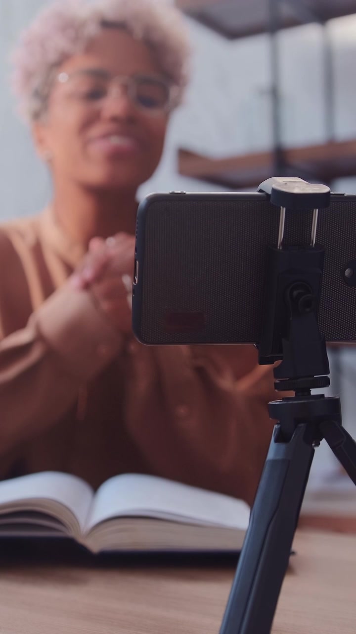 Un smartphone en un trípode graba a una joven mujer afroamericana sonriente en la