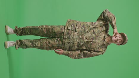 full body of asian man soldier smiling and making call me gesture to camera while standing in the green screen background studio