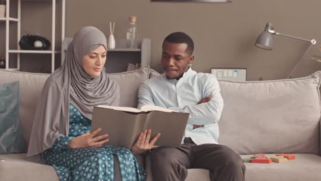 interracial muslim couple reading quran together at home