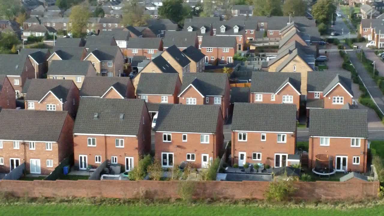 Property ladder new British housing estate aerial view overlooking rooftops low orbit right