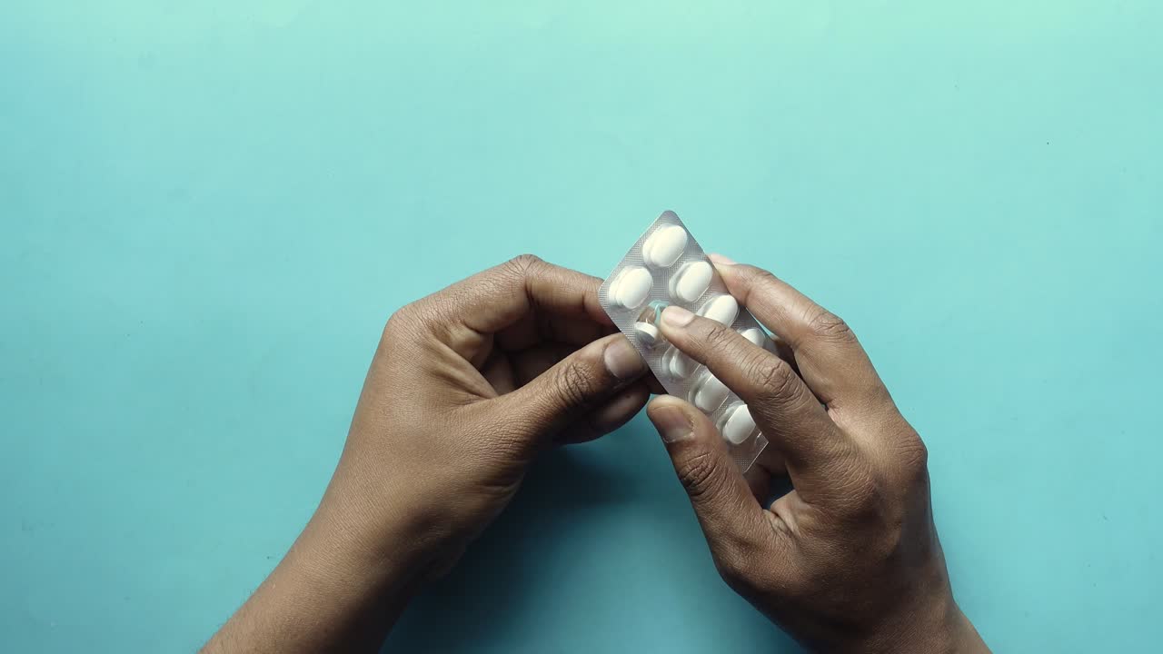Hands opening a blister pack of pills