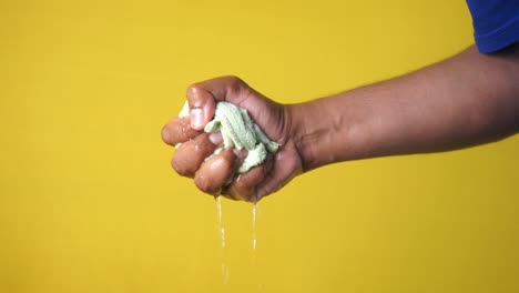 una mano apretando una toalla húmeda, goteando agua